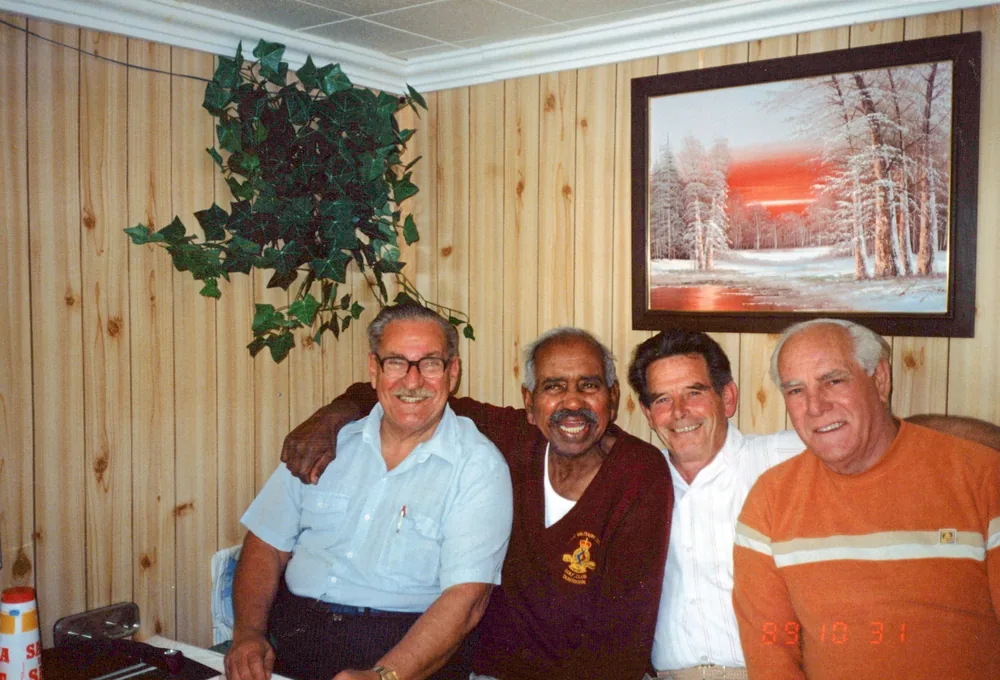 Four men photographed indoors.
