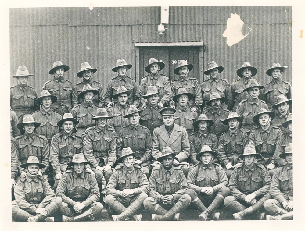 Platoon group photograph in front of a hut.