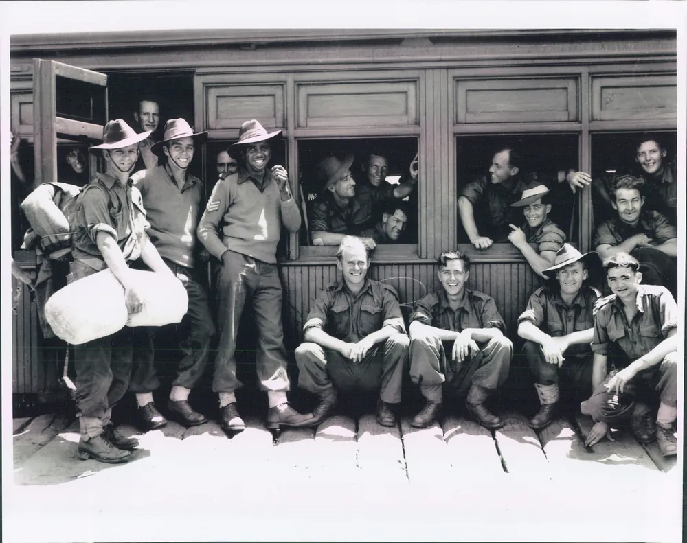 Servicemen beside a train carriage.