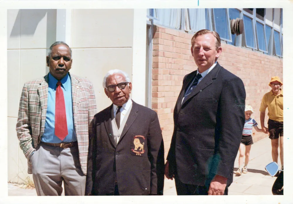 Three men in suits outside a building.