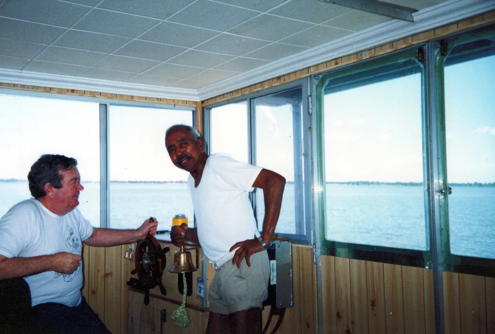 Two men beside a window overlooking water.