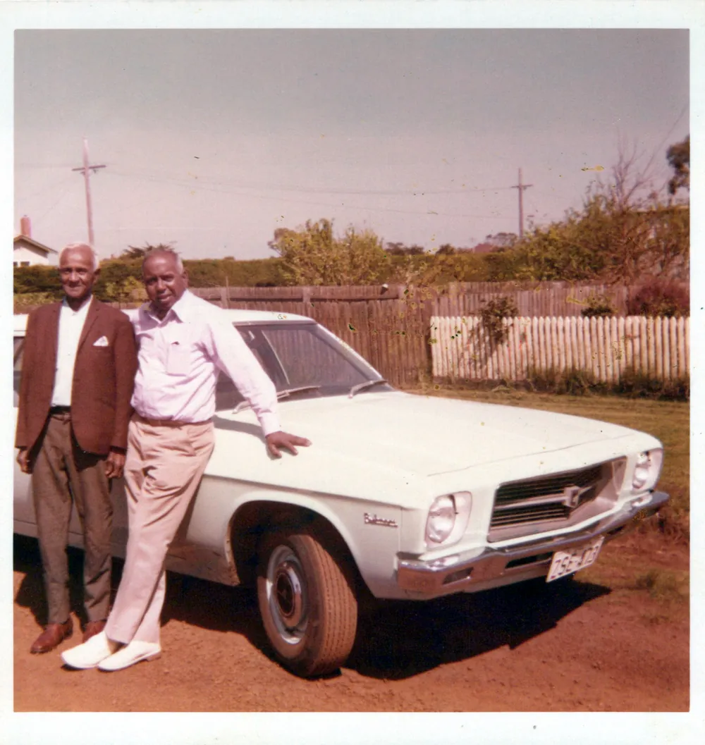 A man leaning against a white sedan.